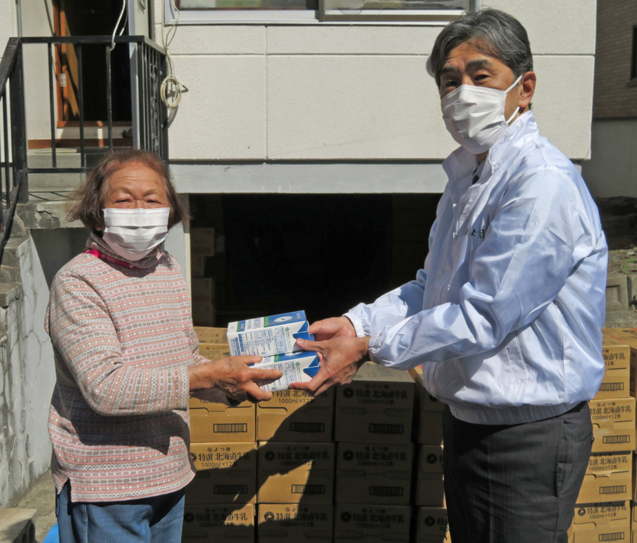 　　　　　　　　　　　牛乳を寄付するよつ葉乳業の林田裕之取締役管理統括部長（右）と、　　　　　　　　　　　　　　それを受け取る小山邦子ハンズハーベスト北海道理事長