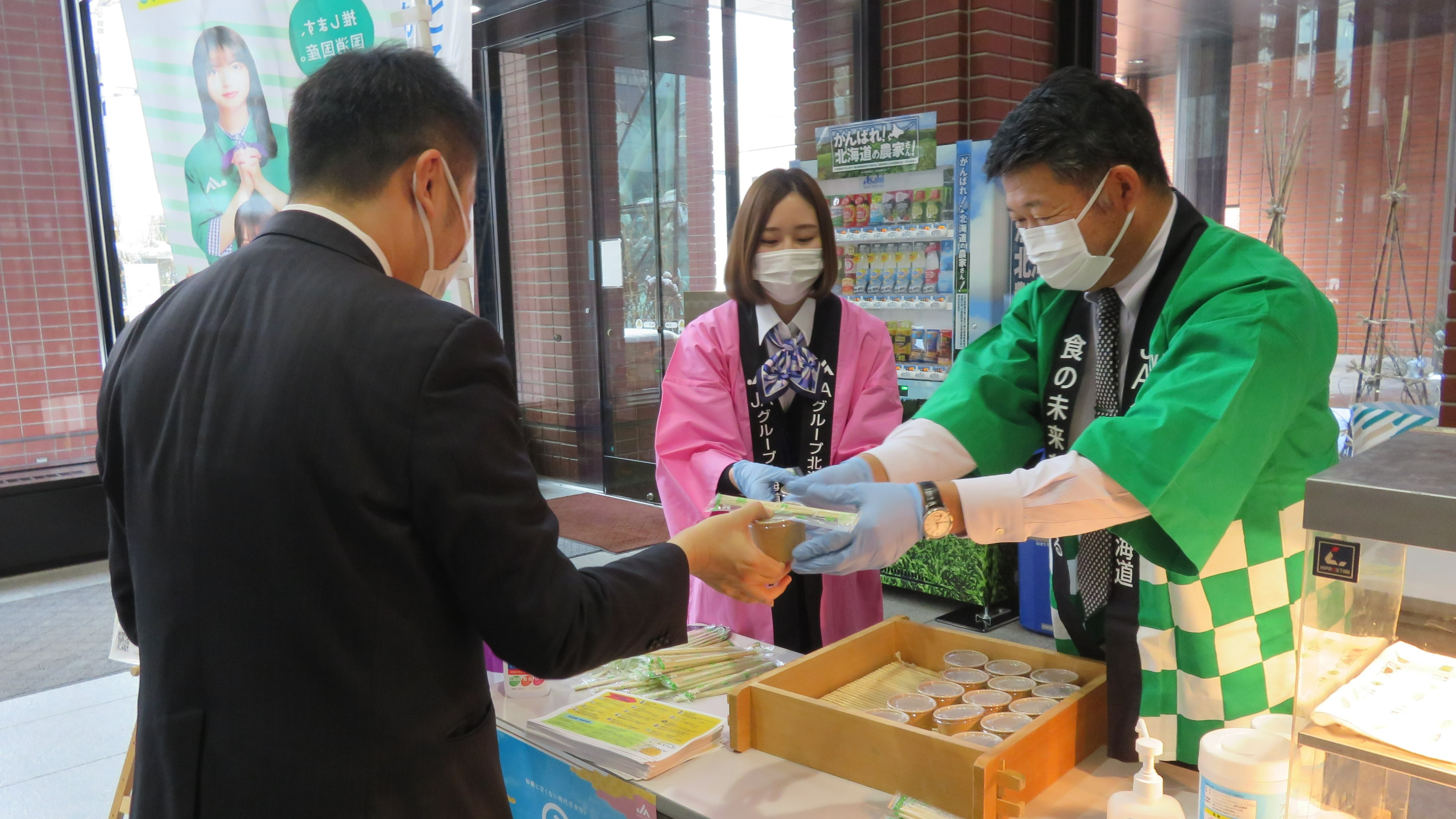 北海道農協中央会の串田雅樹副会長（右）がおしるこを手渡した