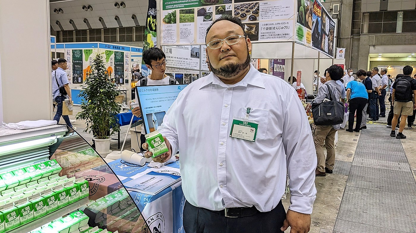 藤井雄一郎日本A2ミルク協会代表。手にしているのはA2ミルクの製品サンプル（アグリフードEXPO会場で撮影）