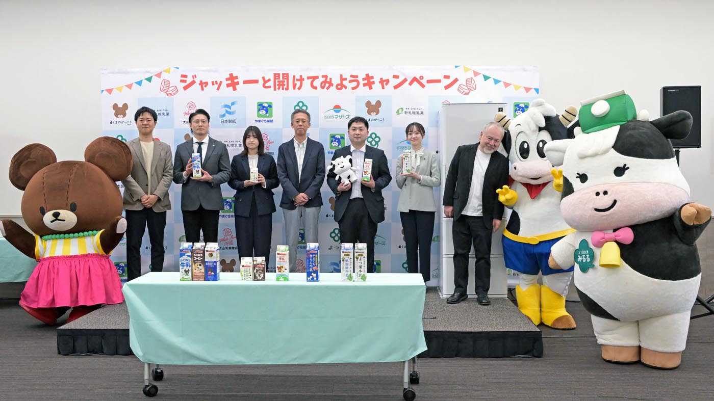 キャンペーンに参加する乳業メーカーと日本製紙の担当者ら。発表会には絵本「くまのがっこう」のキャラクターや乳業メーカーのマスコットも登場した
