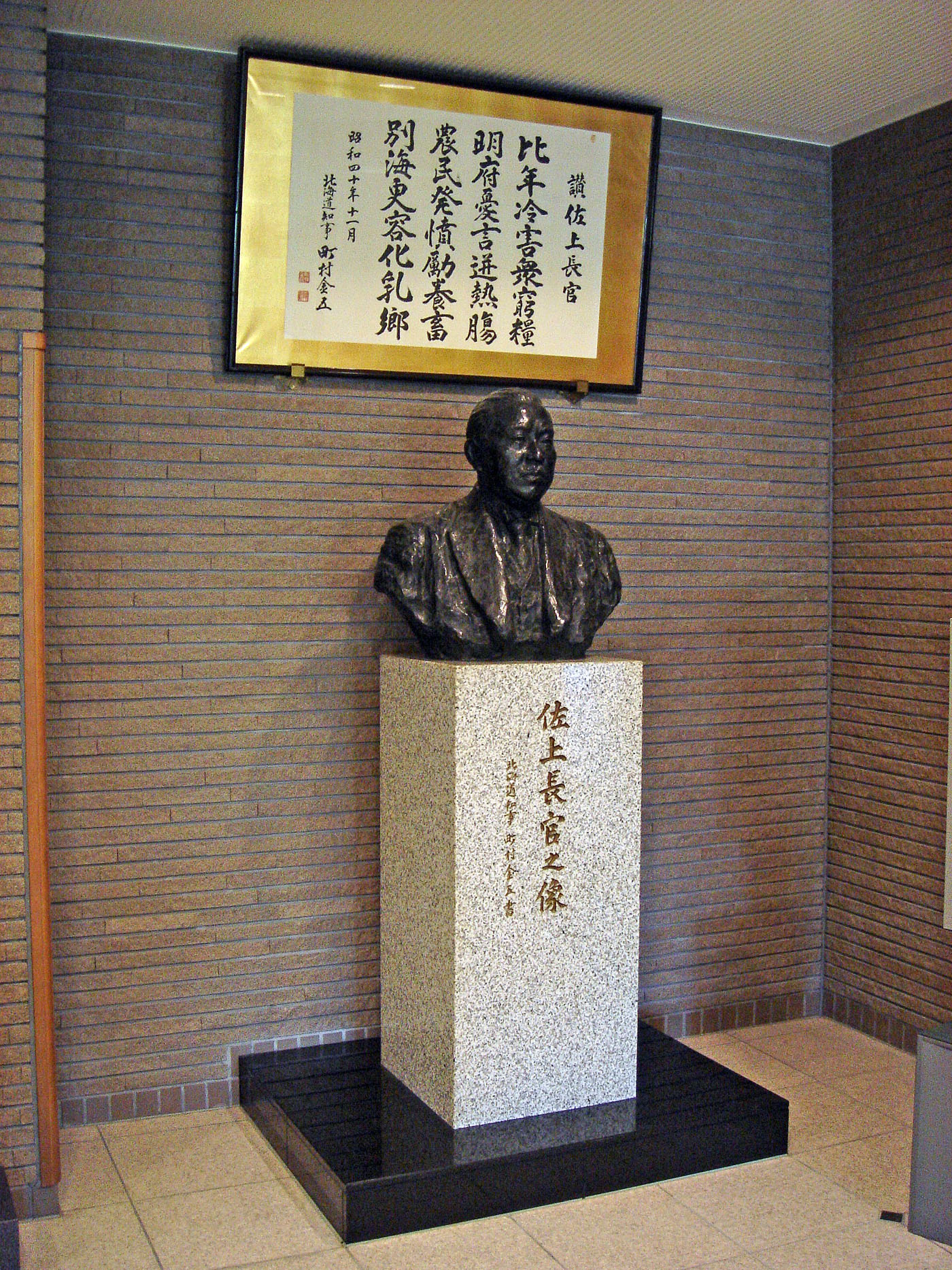 佐上信一長官の胸像と、根室酪農に対する佐上氏の功績をたたえる町村金五道知事の漢詩（昭和40年）。別海町役場ロビーに置かれている