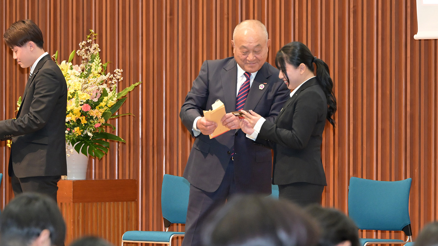 サプライズ贈呈されたチョコレートをみる新入社員（右）と松田社長