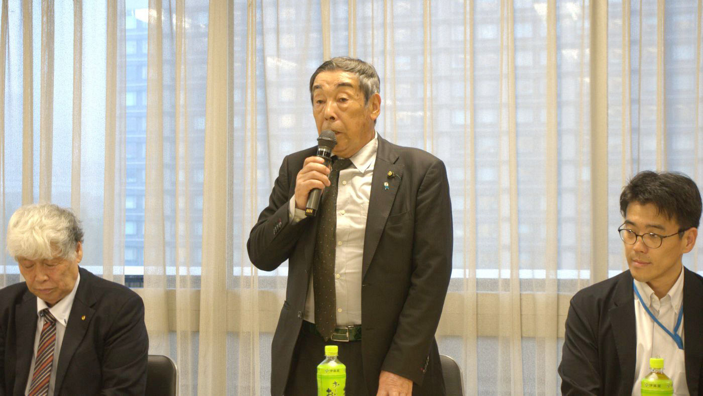 挨拶する臼井勉委員長。右は農水省牛乳乳製品課の平田裕祐課長補佐