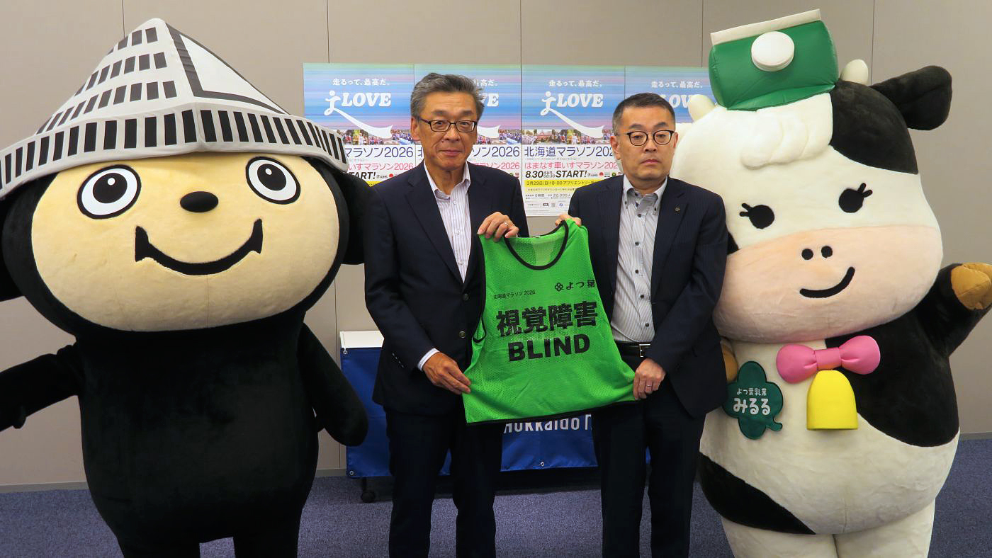 ビブスを手にするよつ葉の蔵田英正総務広報グループ部長（右）と北海道マラソン2026組織委員会の惣田浩・副実行委員長