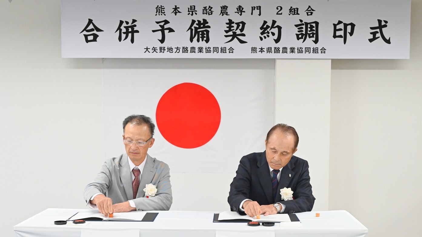 予備調印に臨む熊本県酪農協の山本健二組合長（右）と大矢野地方酪農協の水野幸也組合長